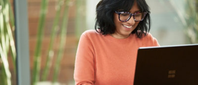 A women wearing glasses working with laptop in smiling face